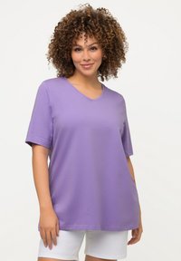 T-shirt lavanda a maniche corte con design a scollo a V. Tessuto morbido e liscio con una vestibilità casual. Abbinato a pantaloni corti bianchi, con dettagli minimali.