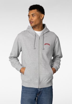 Lysegrå hettejakke med glidelås laget av mykt stoff, med frontlomme og brodert "HENRY CHOICE"-tekst i rødt. Casual passform med snorer.