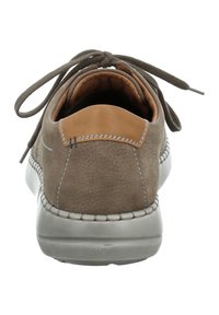 Brązowy skórzany but o gładkiej fakturze, z akcentem z jasnobrązowej skóry na pięcie, szarym gumowym podłożu i dopasowanymi szarymi sznurowadłami.