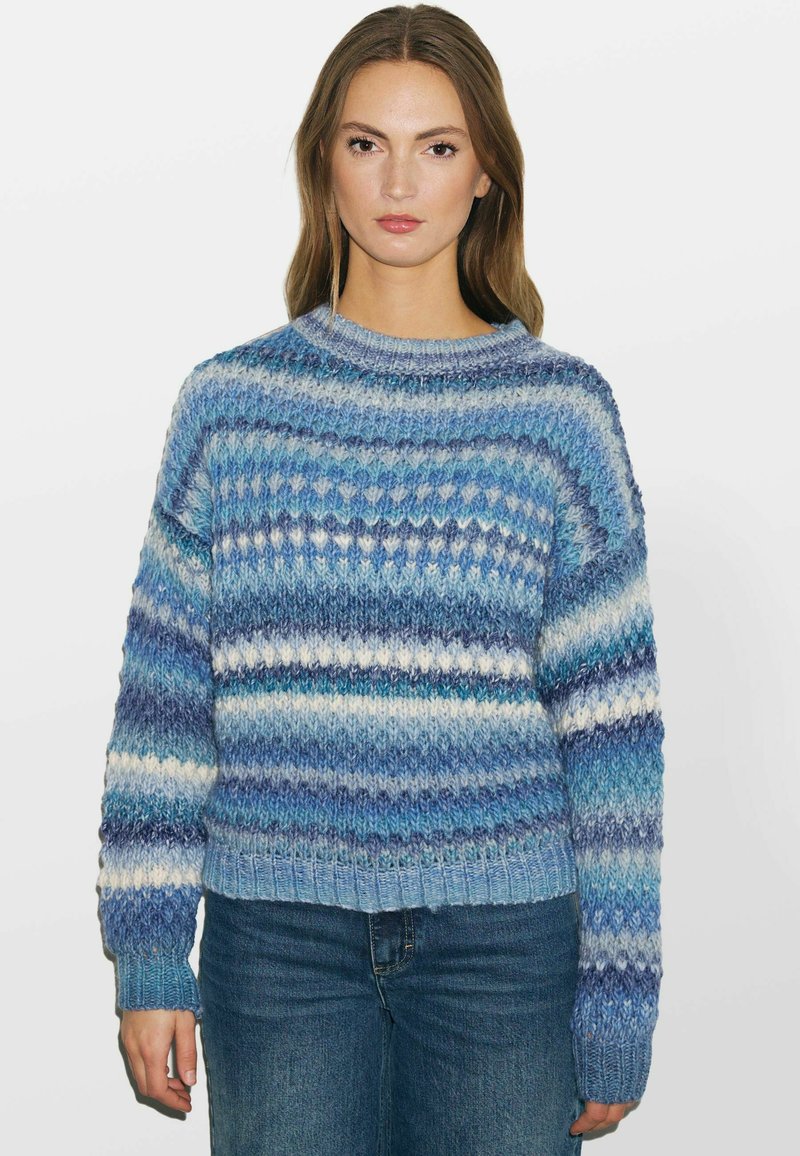 Sinine ja valge triibuline kudumipullover ümmarguse kaelusega ja soonikvarrukatega. Omab tekstuurset mustrit ja lühendatud disaini.