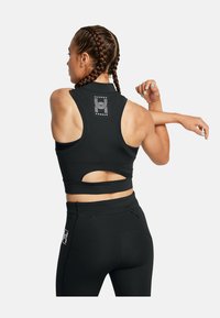 Svart atletisk sportbh med racerback-design, utskärning och logga på baksidan, kombinerad med matchande svarta leggings med ficka.