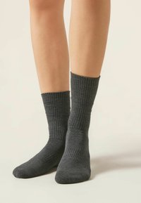 Calcetines de color gris oscuro con textura suave, que tienen un largo hasta la mitad de la pantorrilla y un ajuste ceñido en la parte superior.