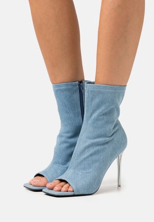 Denim ankelstøvler med strækpasform, peep-toe design og klar stiletthæl. Lynlås bagpå for nem påtagning. Lys blå farve.