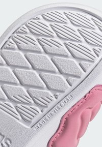 Podešev boty s texturovanou bílou gumou s diamantovými a liniovými vzory; růžové gumové akcenty jsou viditelné podél okraje.