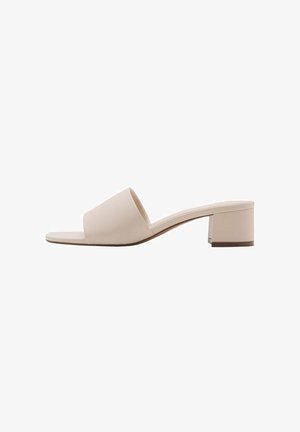 Beige blockhaksandal met een brede band en open teen. Gladde stof en strakke uitstraling. Korte, stevige hak voor stabiliteit.