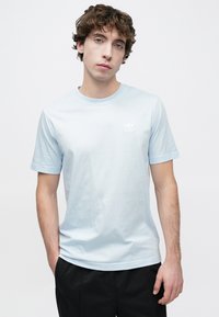 Ανοιχτό μπλε βαμβακερό t-shirt με στρογγυλή λαιμόκοψη και κοντά μανίκια. Διαθέτει ένα μικρό λευκό λογότυπο στο στήθος. Σχεδιασμένο για άνετη εφαρμογή.