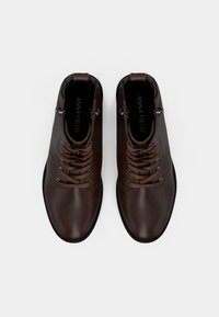 Brązowe skórzane botki za kostkę z wiązanym zapięciem, gładką fakturą i czarną gumową podeszwą. Posiadają metalowy zamek błyskawiczny po boku oraz logo wewnątrz.