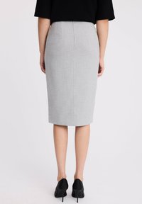 Sukienka o prostym kroju w kolorze szarym, o dopasowanej sylwetce, gładkiej fakturze i średniej długości. Połączona z czarnymi szpilkami.