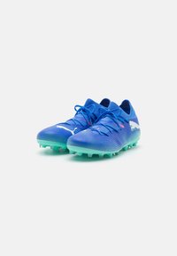 Scarpe da calcio blu con una parte superiore testurizzata, che presenta accenti turchesi e tacchetti. Logo Puma bianco sui lati. Lacci in blu abbinato.