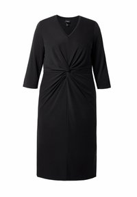 Vestido negro hecho de tela elástica, con escote en V, mangas tres cuartos y detalle de nudo retorcido en la cintura.