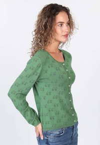 Grüner gestrickter Cardigan mit langen Ärmeln, runder Ausschnitt, Knopfverschluss und einem dezenten Blättermuster auf dem gesamten Stoff.