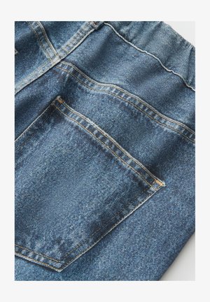 Nahaufnahme von blauen Jeans aus Denim, die die Gesäßtasche mit orangefarbenen Nähten und Details der Stoffstruktur zeigen.