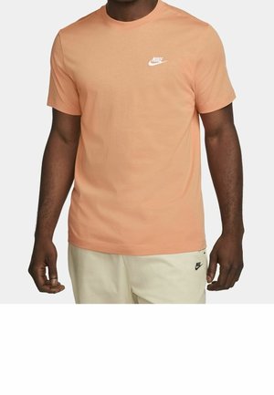 T-shirt orange clair en coton, avec un col rond et des manches courtes, arborant un petit logo Nike blanc sur la poitrine.