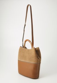 Brown canvas and leather handbag with a structured shape, featuring a top handle and adjustable shoulder strap. Contrast stitching detail.