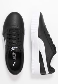 Svarta lädersneakers med rund tå, vit gummisula och vita sidodetaljer. Har snörning och perforerade detaljer på framsidan.