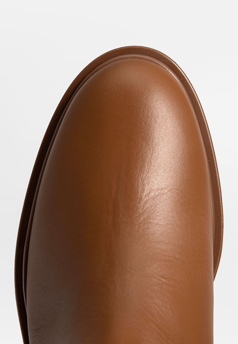 Bruine leren enkellaars met een gladde, glanzende afwerking. Ronde neus en slank silhouet. Stevige zool met minimale details.