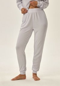 Jasnoszare, ribbedowe spodnie loungewear z elastycznym pasem i dopasowanymi mankietami. Miękka faktura z pionowymi liniami dla dodatkowego detalu.