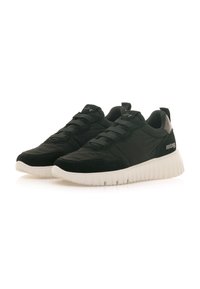 Zapatillas deportivas negras que combinan materiales lisos y texturizados, una suela blanca gruesa y cordones elásticos para un ajuste seguro.