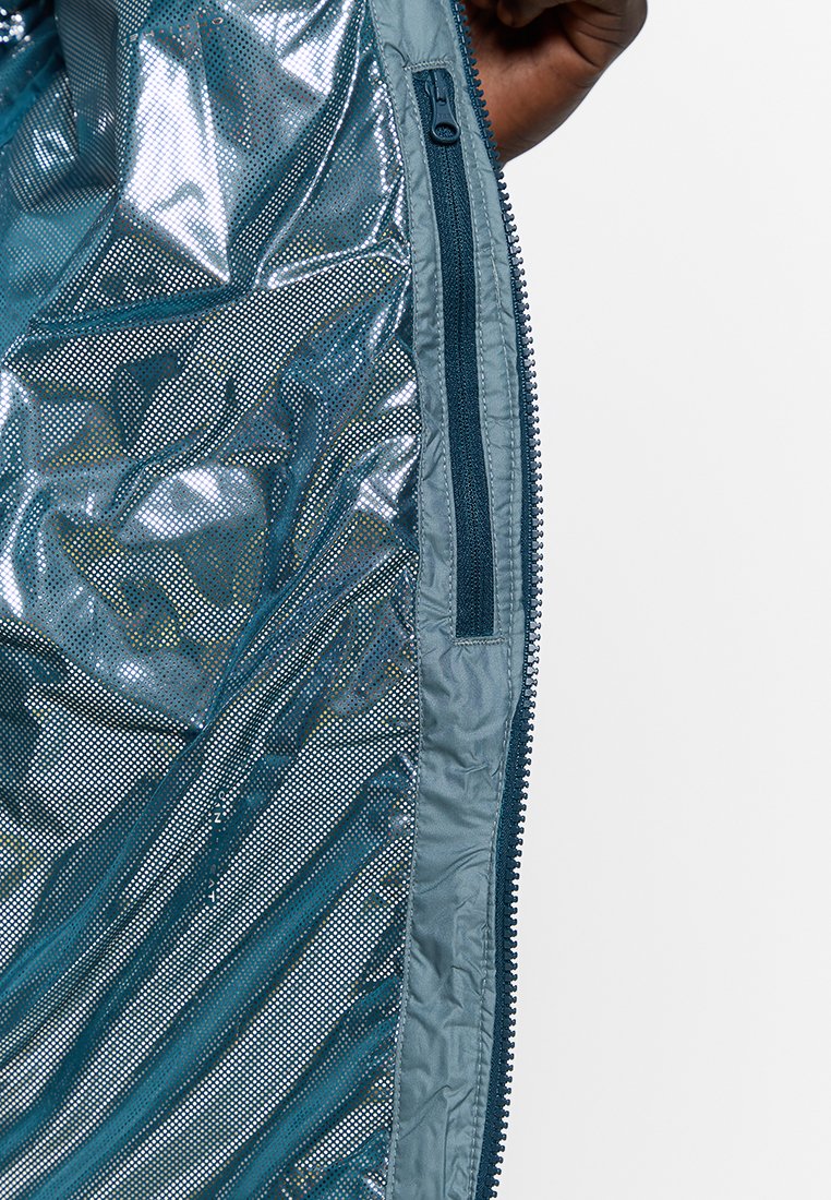 Interno di una giacca azzurra chiaro con una texture lucida, pannelli in rete e una tasca con zip lungo il lato. Chiusura con zip e tessuto liscio.