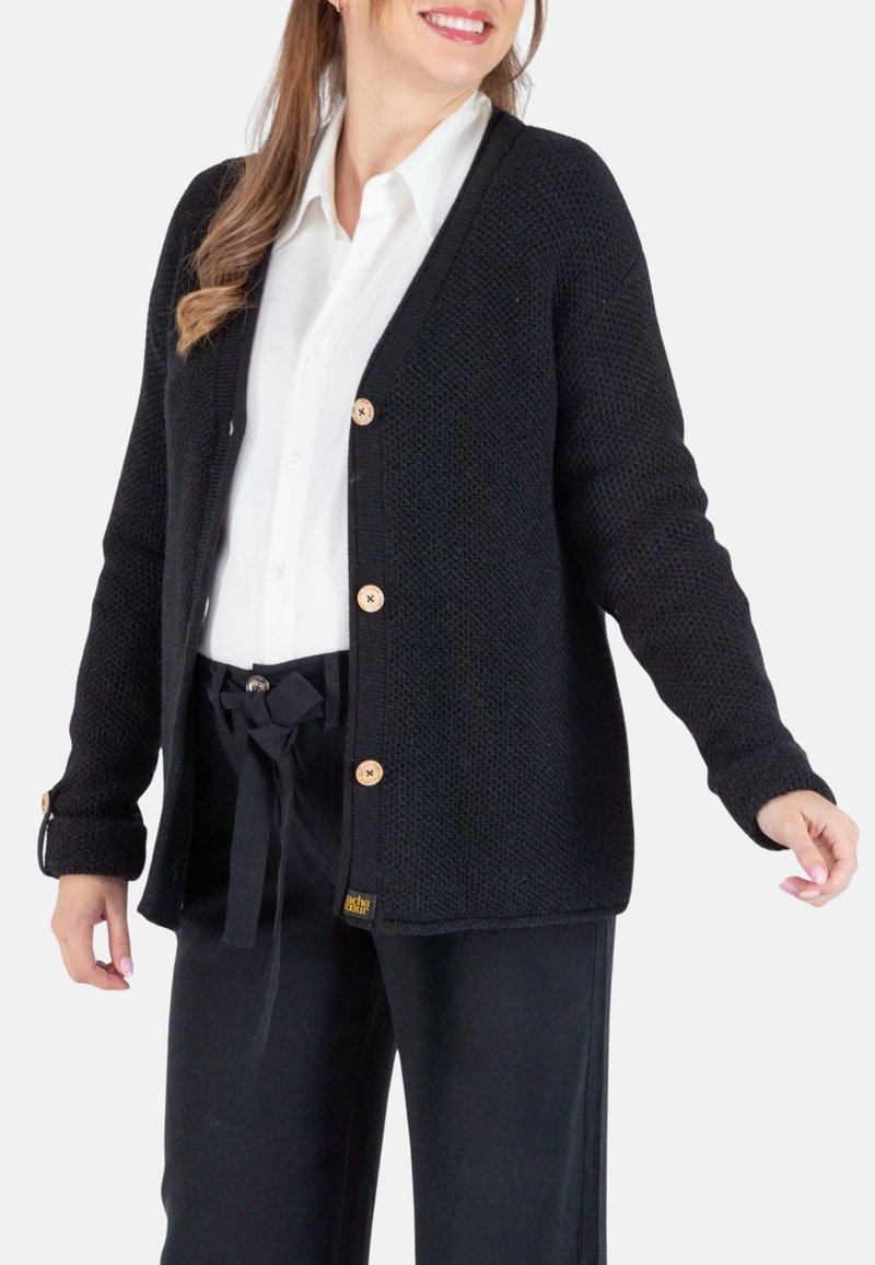 Schwarze Strickjacke mit strukturiertem Gewebe, V-Ausschnitt und Holzknöpfen, kombiniert mit schwarzen hochgeschnittenen Hosen mit einem Bindeband.