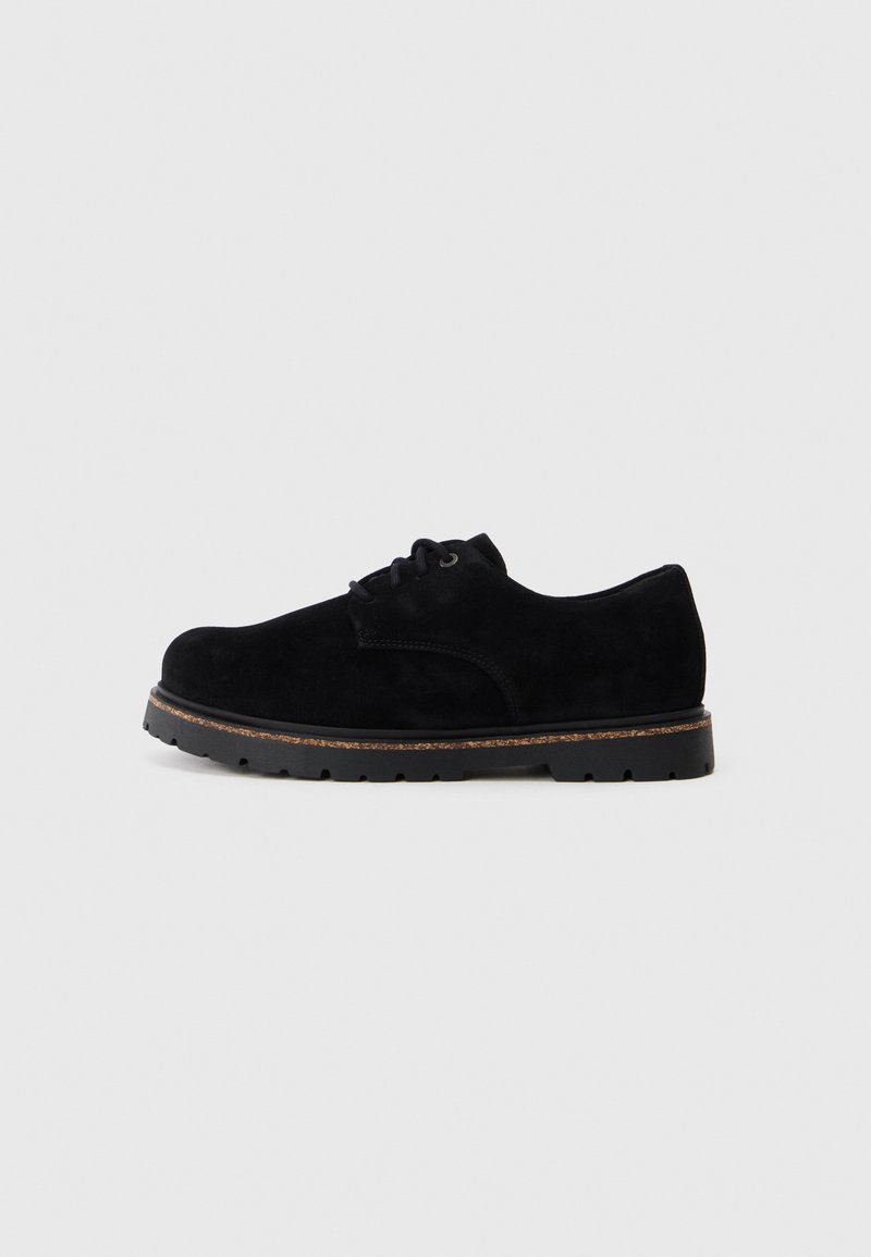 Scarpa in suede nera con lacci, punta arrotondata, texture liscia, suola in gomma e dettagli di cucitura sottile lungo il bordo superiore.