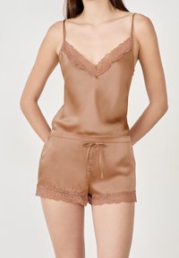Camisole en satin brun avec bordures en dentelle et short assorti avec une taille élastique et des bords en dentelle. Bretelles réglables pour un ajustement parfait.