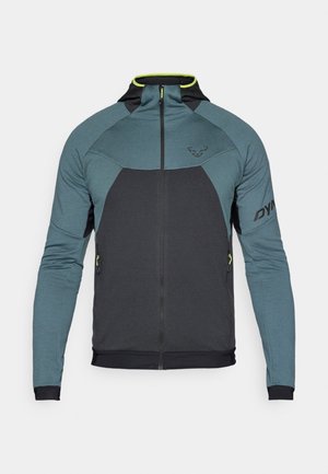 Mikina so šiltom a zipsom v prednej časti, tmavo šedá a tyrkysová farba s farebným blokovaním, hladká textúra a neonovo žlté akcenty.