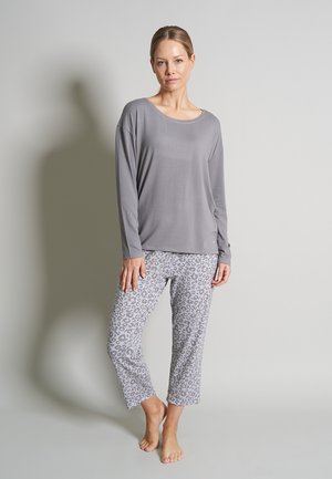 Graues langärmliges Oberteil mit Rundhalsausschnitt, kombiniert mit hellgrauen, leopardgemusterten, cropped Hosen. Weicher Stoff, lockere Passform, keine sichtbaren Hardware-Elemente.