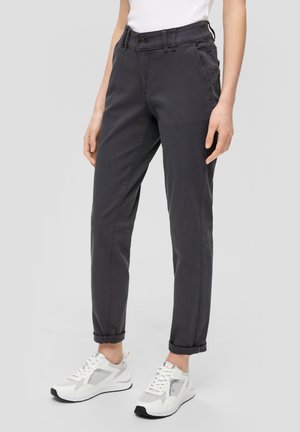 Pantalons gris foncé avec une coupe décontractée, ourlets retroussés et poches avant visibles. Portés avec des baskets blanches avec des accents gris et une tige en mesh.