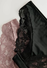 Zwei Paar Unterwäsche; eines in Pink mit floralem Spitzenbesatz, das andere in Schwarz mit ähnlicher Spitze. Beide haben eine weiche, glatte Textur.