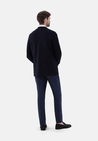 Dunkelblazer mit taillierter Passform, kombiniert mit passenden dunkelblauen Hosen. Weiche Textur und elegantes Design, das minimalistische Akzente aufweist.