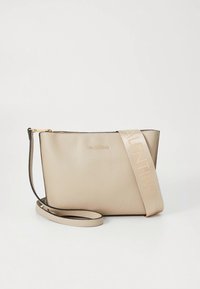 Bézs színű, texturált felületű bőrtáska, logó díszítéssel és levehető, állítható pánttal. Kompakt, téglalap alakú.