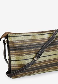 Borsa a tracolla a righe con corpo in tessuto intrecciato in oro e marrone, completata da una tracolla in pelle marrone scuro e dettagli con zip.