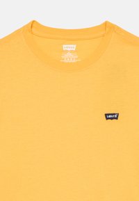 Κίτρινη βαμβακερή μπλούζα με στρογγυλή λαιμόκοψη και κοντά μανίκια. Διαθέτει μικρό μαύρο λογότυπο Levi's κεντημένο στο στήθος.