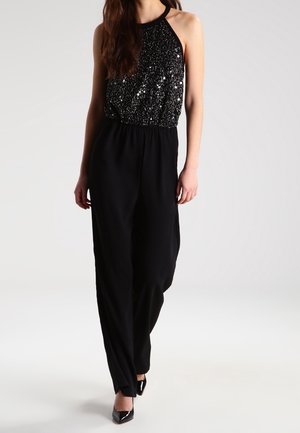 Combinaison noire avec un haut à col halter en sequins et un pantalon large. Texture lisse avec une coupe décontractée et une taille cintrée.