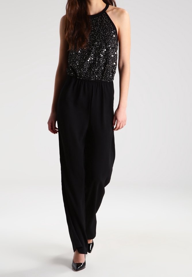 Combinaison noire avec un haut à col halter en sequins et un pantalon large. Texture lisse avec une coupe décontractée et une taille cintrée.