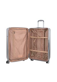 Maleta rígida plateada con exterior texturizado, compartimentos dobles, forro interior beige, bolsillo con cremallera y correas cruzadas para asegurar objetos.