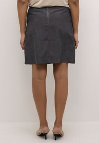 Jupe en denim gris foncé avec fermeture éclair à l'arrière, coupe ajustée et longueur au genou. Design simple sans motifs.