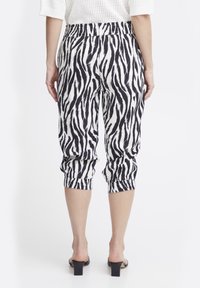 Pantaloni a cropped a righe zebrate in bianco e nero, con vita elasticizzata e polsini arricciati, realizzati in un tessuto leggero.