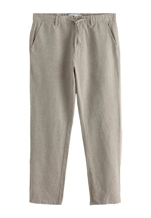 Egy személy jobb karja és keze, aki bézs rövid ujjú inget és világosszürke, texturált nadrágot visel oldalzsebbel és övjárattal.