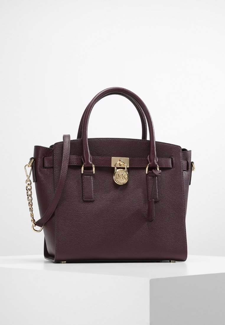 Sac à main en cuir bordeaux avec double anses, bandoulière en chaîne amovible, quincaillerie dorée et fermoir à l'avant. Fini texturé avec des détails élégants.