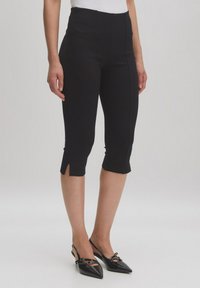 Zwarte cropped broek met een hoge taille en zijsplitten aan de zoom, gemaakt van een gladde stof, gecombineerd met zwarte puntige slingback schoenen.