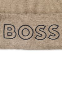 Beanie lavorato a maglia color beige con risvolto, con la scritta "BOSS" in evidenza in caratteri blu scuro. Texture morbida, design casual.