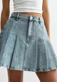 Denim-Rock im Skater-Stil in Hellblau mit plissiertem Design, mit einer taillierten Passform und Knopfverschluss. Weiche Textur mit sichtbaren Nähdetails.