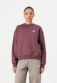 Burgundia puuvillasegistusest valmistatud sviiter, millel on klassikaline ümar kaelus, üle mõõtmete lõige ja rinnal väike valge logo.