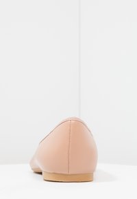 Nackte Leder-Ballettschuhe mit abgerundetem Zehenbereich, glatter Textur und einer flachen, natürlichen Gummisohle. Sichtbare Nähte entlang der Kanten.