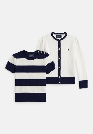 Tumši zils un balts svītrains kokvilnas krekls ar apaļu kakla izgriezumu un pogu akcentiem; derīgs džemperis ar pērļu pogām un logotipa izšuvumu.