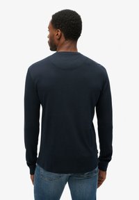 Marineblå langærmet skjorte i blødt stof med rund hals og ribbede manchetter, der har et glat bagdesign og minimalistisk stil.