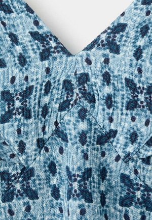 Blue and teal fabric with dark blue floral and dot pattern, showing textured weave and V-shaped seam detail.