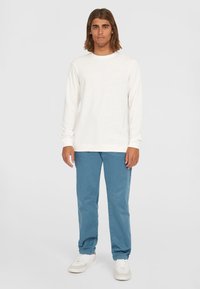 Hvid langærmet skjorte med et tekstureret mønster, lagt sammen med lyseblå bukser og hvide sneakers. Casual outfit med en afslappet pasform.